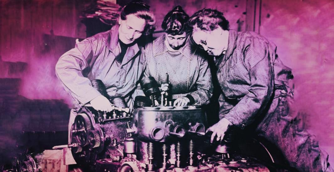 Three ladies working on an engine